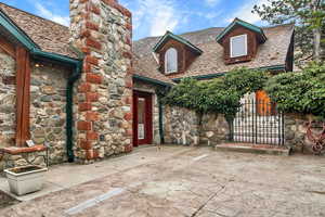 View of exterior entry featuring stone siding, a gate, and a chimney