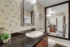 Bathroom with vanity and wallpapered walls