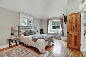 Bedroom featuring lofted ceiling, light wood-style flooring, and multiple windows