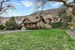 View of front of house featuring a porch, a front yard, a chimney, a mountain view, and stone siding