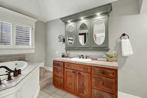 Full bath with vanity, light tile patterned floors, and a garden tub
