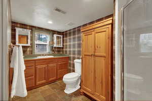 Bathroom featuring wallpapered walls, vanity, a shower stall, and recessed lighting