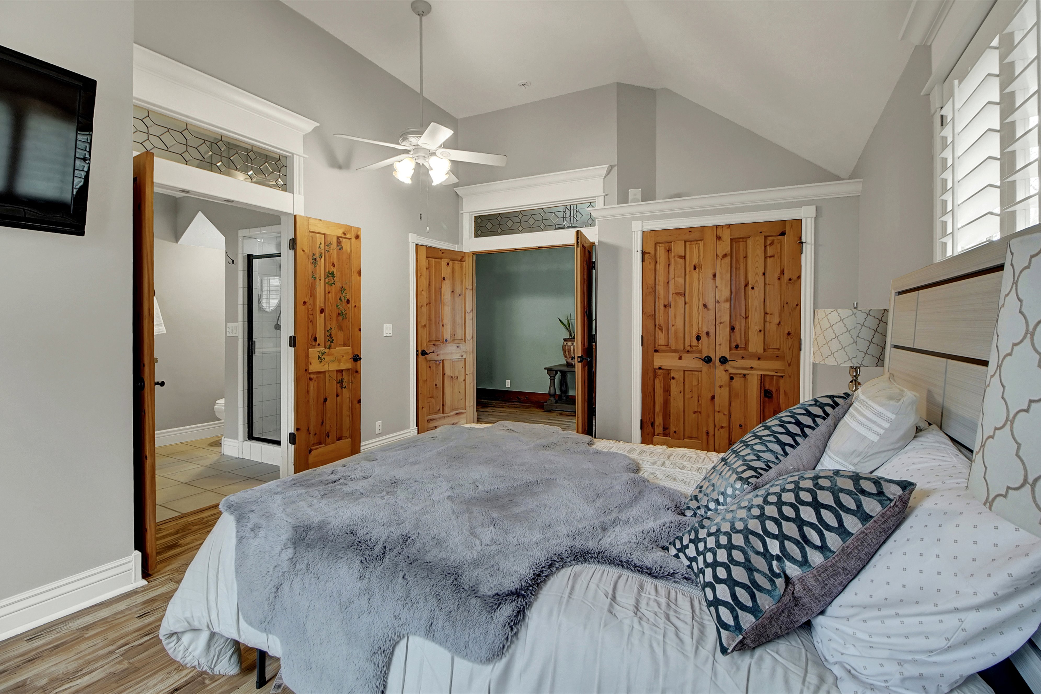 Bedroom with light wood-style floors, vaulted ceiling, a closet, ceiling fan, and connected bathroom