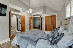Bedroom with light wood-style floors, vaulted ceiling, a closet, ceiling fan, and connected bathroom