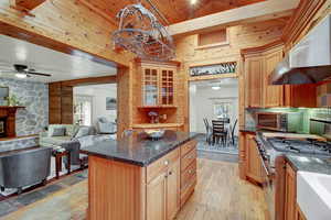 Kitchen with dark stone countertops, extractor fan, a center island, glass insert cabinets, and stainless steel appliances