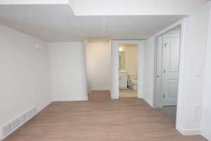 Empty room with a textured ceiling and light wood-type flooring