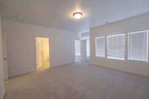 Unfurnished bedroom with light carpet and baseboards