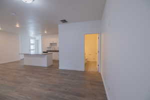 Kitchen featuring dark countertops, white cabinets, a center island, dark wood-type flooring, and open floor plan