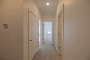 Hallway featuring light colored carpet and attic access