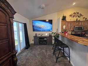 Living area featuring lofted ceiling and dark carpet
