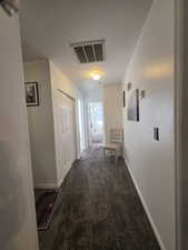 Corridor with dark colored carpet and baseboards