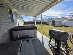 Fenced backyard featuring grilling area, a patio, a storage unit, a hot tub, and a residential view