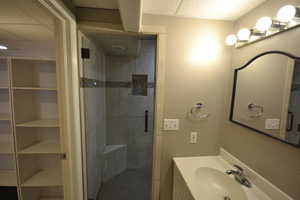 Bathroom with a shower stall, vanity, and a closet