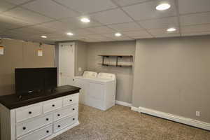 Laundry area with a baseboard heating unit, light colored carpet, recessed lighting, separate washer and dryer, and a paneled ceiling