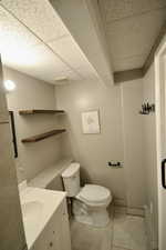 Bathroom featuring a paneled ceiling, vanity, and light tile patterned flooring