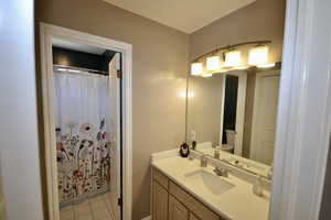 Full bathroom with vanity, light tile patterned floors, and a shower with shower curtain