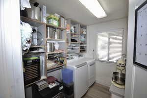 Laundry room featuring light wood-style floors, washing machine and dryer, and a textured ceiling