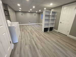 Finished basement with a drop ceiling, light wood finished floors, recessed lighting, and independent washer and dryer