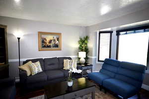 Living area with a textured ceiling, wood finished floors, and baseboard heatingAI enhanced