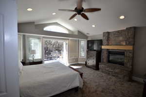 Bedroom with recessed lighting, access to exterior, dark carpet, a stone fireplace, and ceiling fan