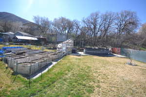 Fenced yard with a covered pool, a vegetable garden, a patio area, a mountain view, and a greenhouse