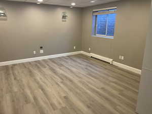 Spare room with a paneled ceiling, a baseboard radiator, light wood finished floors, and recessed lighting