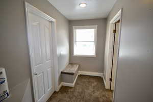 Corridor with dark carpet, a textured ceiling, and baseboard heating
