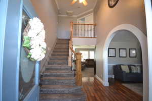 Stairway featuring a high ceiling, wood finished floors, crown molding, and arched walkways