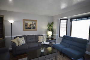 Living room featuring wood finished floors, a textured ceiling, and baseboard heating