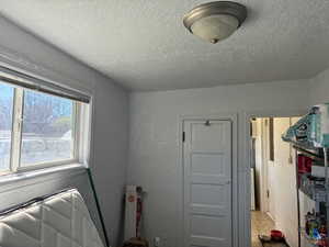 Laundry room featuring a textured wall and a textured ceiling