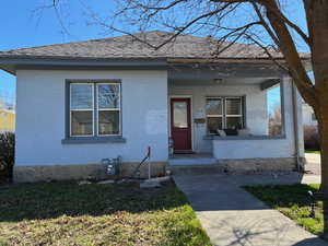 Bungalow featuring covered porch, brick siding, and a front lawn