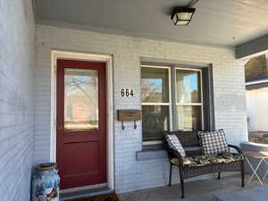 View of exterior entry featuring brick siding and covered porch