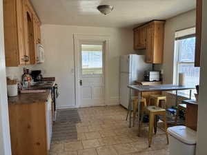 Kitchen featuring dark countertops, white appliances, and wood finish cabinetry