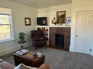 Carpeted living area with a textured ceiling and a wood stove
