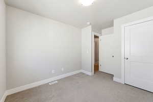 Unfurnished bedroom with light colored carpet and baseboards
