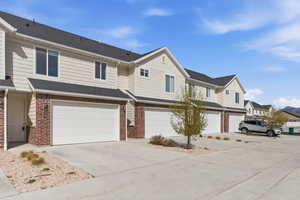 Traditional-style home with brick siding, driveway, a shingled roof, an attached garage, and a residential view