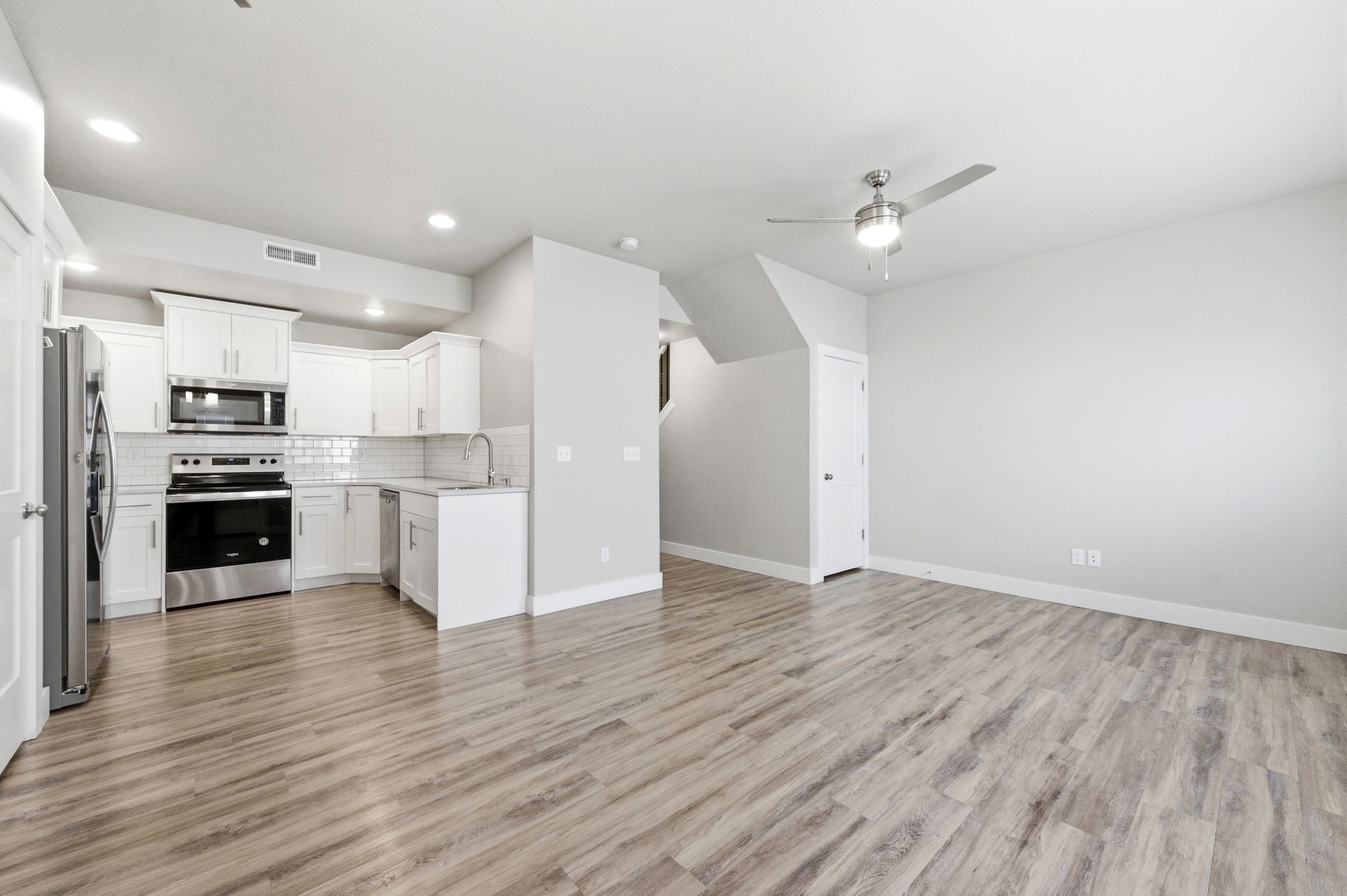 Kitchen with open floor plan, stainless steel appliances, tasteful backsplash, light countertops, and ceiling fan