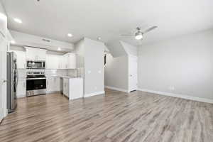 Kitchen with open floor plan, stainless steel appliances, tasteful backsplash, light countertops, and ceiling fan