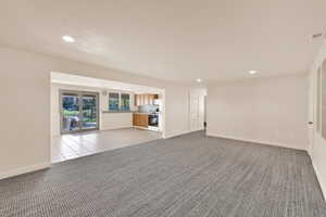 Unfurnished living room featuring light colored carpet, recessed lighting, and light tile patterned floors