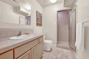Bathroom with a shower stall, vanity, light tile patterned flooring, and tasteful backsplash