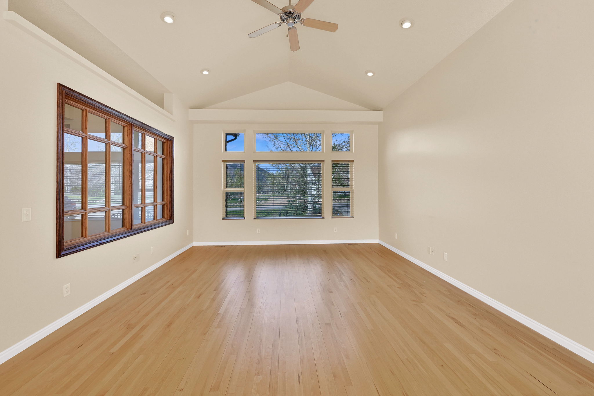 Empty room featuring ceiling fan, light wood-style floors, lofted ceiling, and recessed lighting