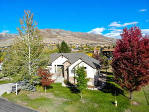 View of front of house featuring a front yard, a mountain view, and stone siding
