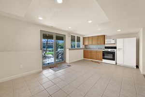 Kitchen featuring white appliances, light countertops, light tile patterned floors, recessed lighting, and decorative backsplash