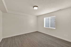Spare room with dark colored carpet and baseboards