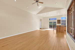 Unfurnished living room with light wood finished floors, vaulted ceiling, a ceiling fan, and recessed lighting