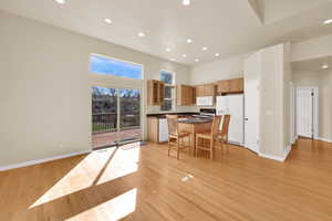 Kitchen with glass insert cabinets, a kitchen island, white appliances, a high ceiling, and recessed lighting