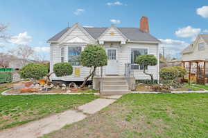 View of front of house with a front lawn, a chimney, and roof with shingles
