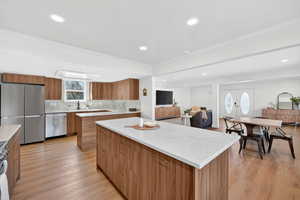 Kitchen with stainless steel appliances, wood finish cabinetry, modern cabinets, light wood-style flooring, and a kitchen island