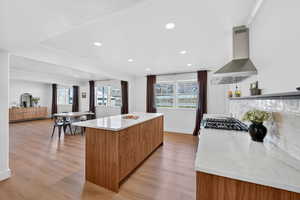 Kitchen featuring recessed lighting, a center island, modern cabinets, wood finish cabinetry, and light stone countertops