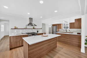 Kitchen with wood finish cabinets, modern cabinets, ventilation hood, stainless steel appliances, and recessed lighting